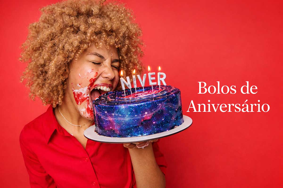 Imagem vibrante com fundo vermelho mostrando uma mulher de cabelos cacheados dourados com o rosto sujo de bolo, prestes a morder um bolo de aniversário galáxia (azul e roxo brilhante). O bolo tem velas que formam a palavra