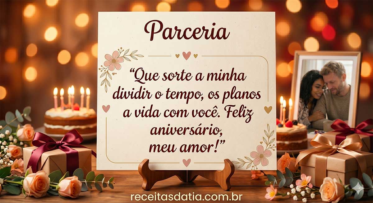 Um cartão de aniversário romântico com o título "Parceria" em destaque. No centro, a mensagem: "Que sorte a minha dividir o tempo, os planos a vida com você. Feliz aniversário, meu amor!". O cartão está apoiado em um suporte de madeira sobre uma mesa decorada com bolos com velas acesas, presentes com laços, flores e um porta-retrato com a foto de um casal sorrindo. O fundo tem luzes bokeh suaves. No rodapé, a marca receitasdatia.com.br.